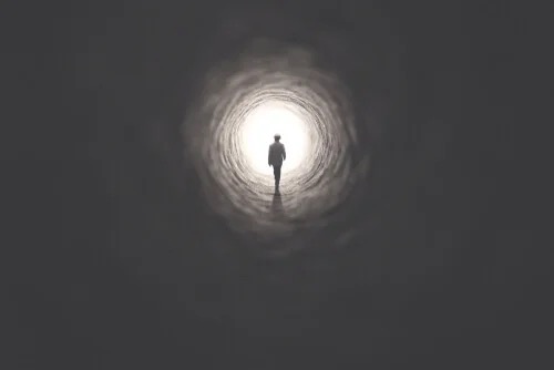 A figure walking into a tunnel.