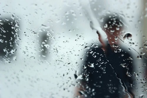 A figure seen through a rainy window.