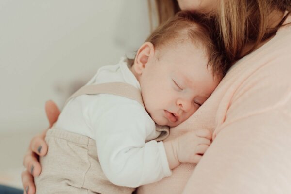 A baby sleeping on a woman's chest.