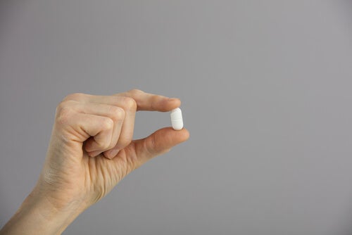 A hand holding a pill.