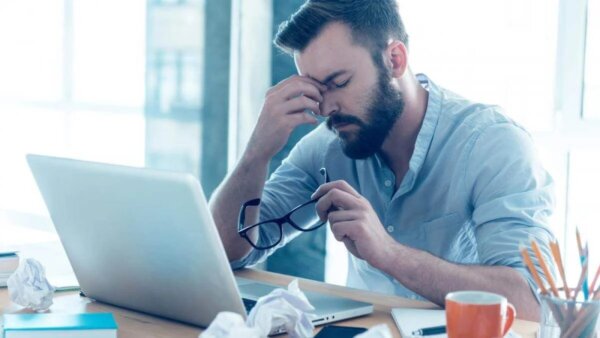 A man at his computer looking tired, who could benefit from feierabend.