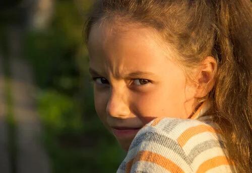 A little girl frowning.