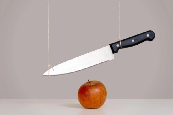 Hängande kniv över äpple