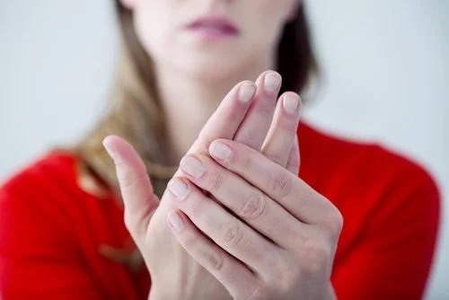 A woman with pain in her hands, a symptom of Parkinson's disease.
