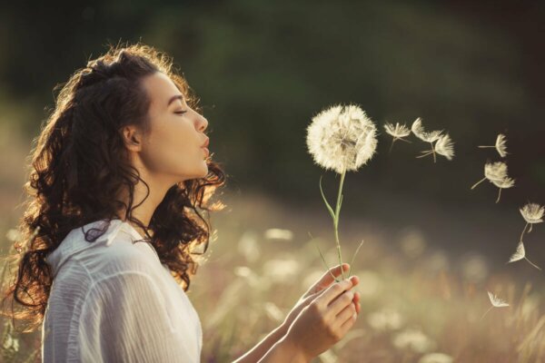 A woman blowing a dandelion.