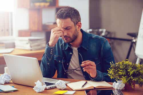 Træt mand ved skrivebord prøver at finde den psykologiske nøgle til iværksætteri