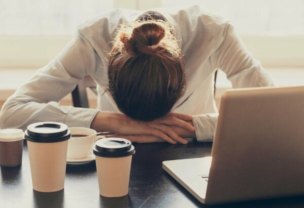 Exhausted woman with her head on the table showing what lies behind laziness.