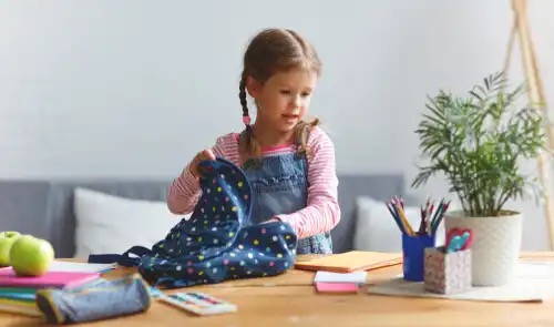 A child unpacking her backpack.