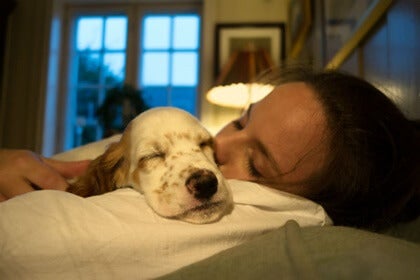 A woman sleeping with her dog.