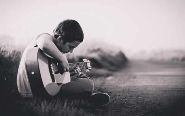 En trist gutt som spiller gitar.