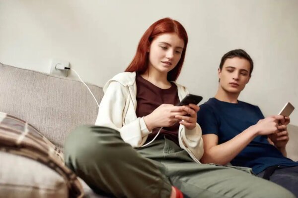 Dwóch młodych ludzi korzysta ze swoich telefonach komórkowych.