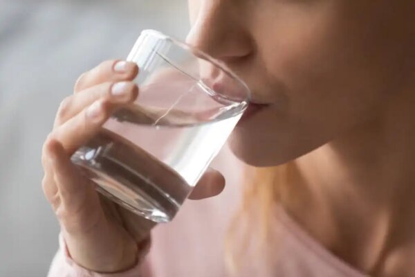 A woman drinking a glass of water.