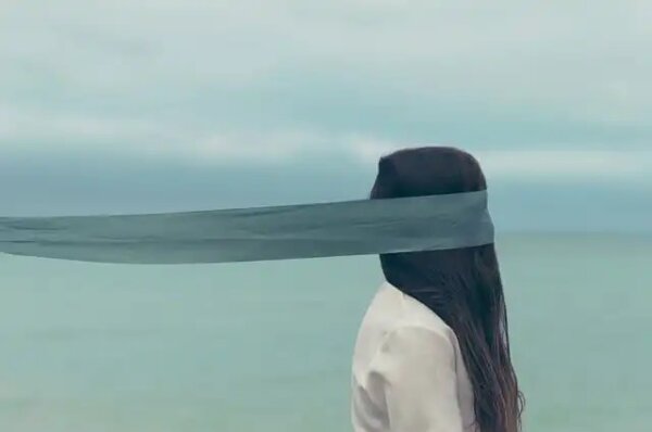 Vrouw met een lange blinddoek aan zee