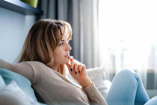 An image of woman on sofa holding her chin.