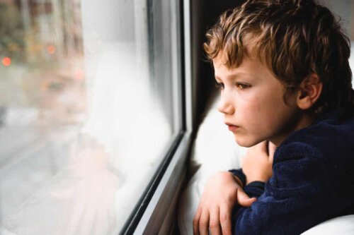 A melancholy child looking out a window.