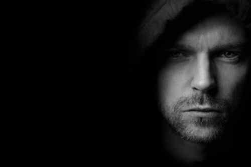 A man in a hood showing signs of the dark triad of personality.