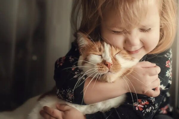 Een klein meisje dat een kat knuffelt