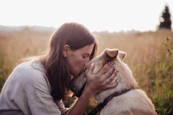 Een vrouw die haar hond kust