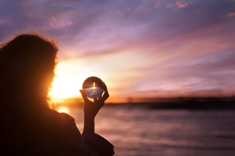Woman gazing through a crystal ball at a sunset, symbolizing introspection
