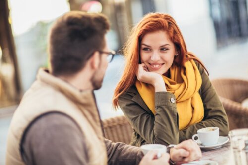 A woman smiling while turning toward a man and making eye contact with him.