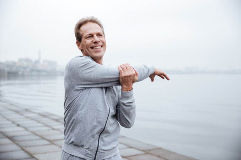 A man stretching while exercising along the shore.